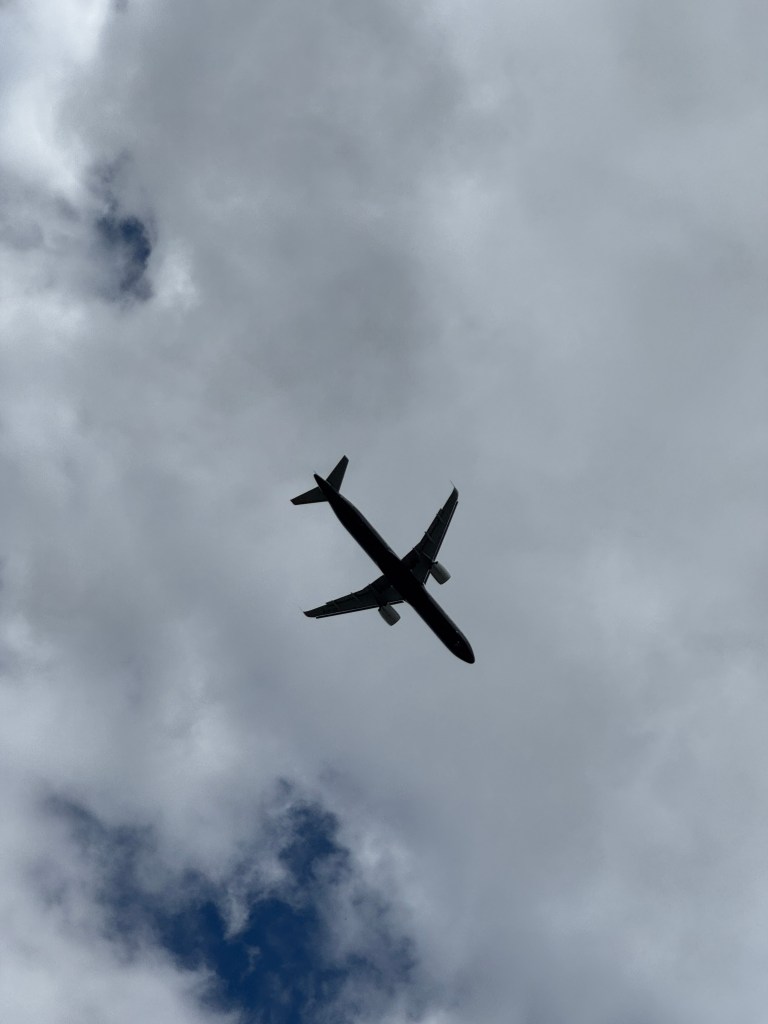 An airplane flying through a cloudy sky, viewed from below.